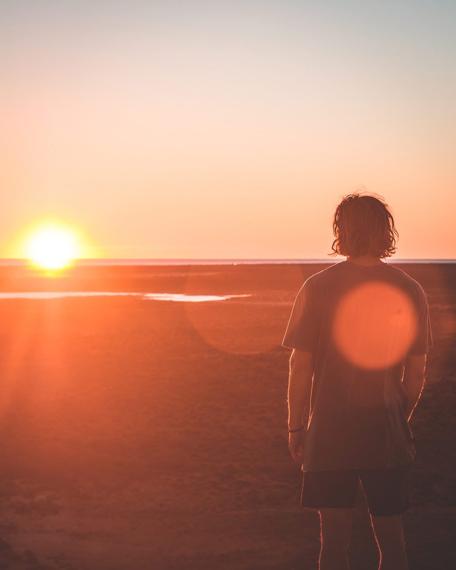 Joven mirando el atardecer en la playa